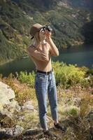 fotografo turista viaggiatore in piedi sulla cima verde sulla montagna tenendo in mano la fotocamera digitale foto