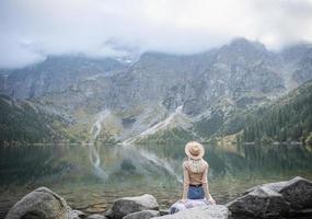 giovane donna in un'escursione seduta su una roccia foto