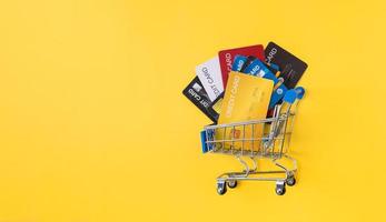 pila di carte di credito nel carrello su sfondo giallo. concetto di pagamento online. foto