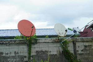 parabola satellitare arancione per la ricezione dei segnali tv attaccata al tetto della casa per essere in posizione elevata e aperta per ricevere bene i segnali foto