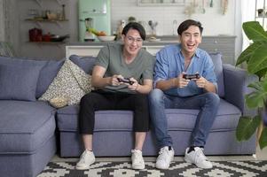 giovane coppia gay sorridente che gioca ai videogiochi nel soggiorno di casa, lgbtq e diversità foto