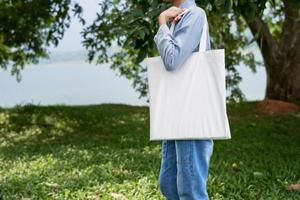 giovane donna che tiene borsa di cotone su sfondo verde foto