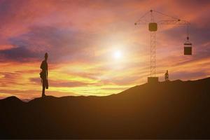 obiettivi costruzione uomo in piedi sulla cima di un cantiere di montagna a guardare il tramonto foto