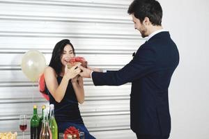 coppia dolce amore felice con confezione regalo a sorpresa fidanzata nel periodo natalizio e festa di capodanno, decorazione di San Valentino con albero di Natale, palloncini colorati e scatole regalo nell'area dispensa foto