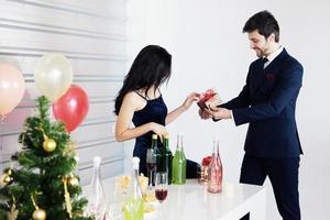 coppia dolce amore felice con confezione regalo a sorpresa fidanzata nel periodo natalizio e festa di capodanno, decorazione di San Valentino con albero di Natale, palloncini colorati e scatole regalo nell'area dispensa foto