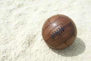 pallone da calcio marrone vintage calcio sfondo spiaggia di sabbia foto
