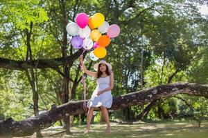 giovane ragazza adolescente seduta su un albero e con palloncini in mano foto