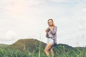 giovane donna hipster con fotocamera retrò che cattura il paesaggio all'aperto, la natura della montagna di stile di vita sullo sfondo. foto