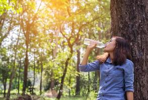 bella giovane donna acqua potabile al mattino dopo aver finito di fare jogging foto