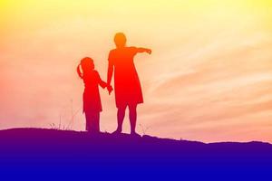 la madre ha incoraggiato suo figlio all'aperto al tramonto, concetto di silhouette foto