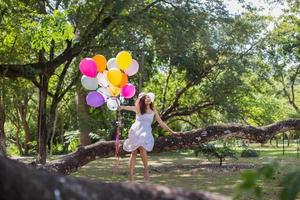 giovane ragazza adolescente seduta su un albero e con palloncini in mano foto