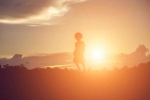 sagoma del bambino, momenti di gioia del bambino. sul tramonto della natura foto