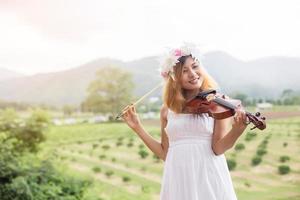 giovane musicista hipster donna che suona il violino nello stile di vita all'aperto della natura dietro la montagna. foto