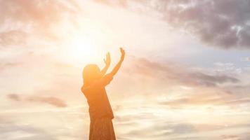 silhouette di donna che prega su sfondo bellissimo cielo foto