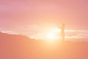 silhouette di donna che prega su sfondo bellissimo cielo foto