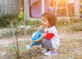 bambina che innaffia albero con annaffiatoio foto