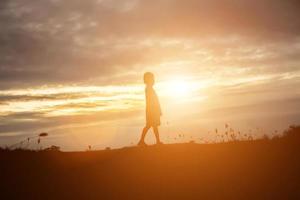 sagoma del bambino, momenti di gioia del bambino. sul tramonto della natura foto