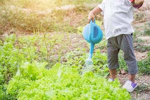 bambina che innaffia albero con annaffiatoio foto