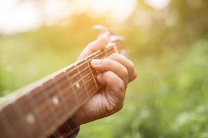 giovane donna hipster che suona la chitarra per rilassarsi durante le sue vacanze, godersi l'aria fresca e naturale. foto