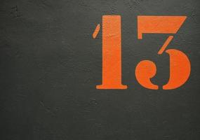 un numero 13 stilizzato arancione su sfondo nero