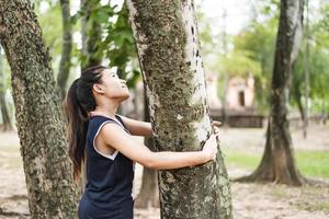 giovane donna che abbraccia un grande albero, ama il concetto di natura. foto