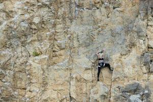 ragazza estrema, scalatrice su una roccia grigio-rossa a strapiombo nelle montagne della Crimea. foto