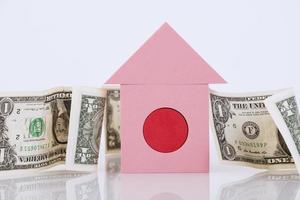una casetta rosa si staglia sullo sfondo delle banconote americane, uno sfondo bianco. il concetto di prestito bancario garantito da immobili, mutui, tasse fondiarie. copia spazio. foto