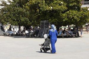 yalta, ucraina, 26 luglio 2021 - donna musulmana in abiti blu con una carrozzina sull'argine a gorda, vista dal retro foto