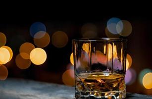 whisky single malt in un bicchiere di whisky in una notte d'estate con il bokeh della città sullo sfondo foto