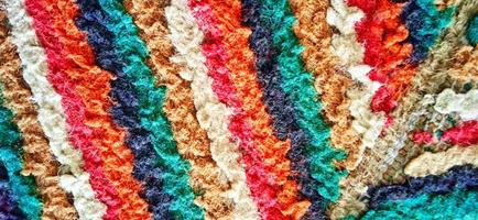 trama di moquette tessuta dritta multicolore variegata. materiale tessile fuzzy sottile grunge linea verticale. tappeto riccio effetto tessuto. foto