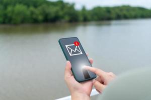 la mano di una donna invia e riceve e-mail sul suo smartphone. concetto di tecnologia di comunicazione aziendale. foto