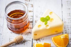 fatto in casa di torta al cioccolato bianco fresco a forma di formaggio putt su tavola di legno bianca e menta, arancia, cucchiaio di miele e miele. concetto di cibo dolce e dessert. dolci decorati per le vacanze. avvicinamento. foto