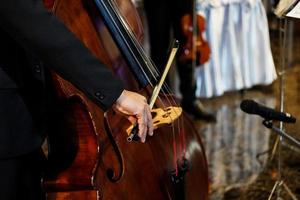 primo piano la mano del musicista sta suonando il contrabbasso in un evento al coperto foto