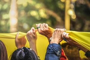 le persone unite mano sulla bandiera gialla foto