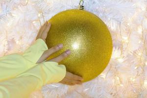 la mano della donna per prendere la palla di natale foto