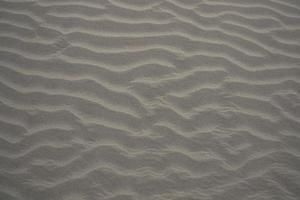 consistenza della sabbia. sfondo strutturato di sabbia ondulata. spiaggia di sabbia strutturata foto