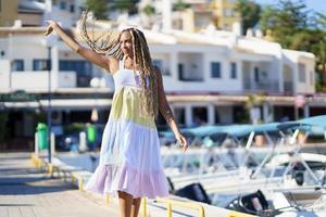 donna nera che cammina lungo un porto marittimo con indosso un bel vestito estivo. foto