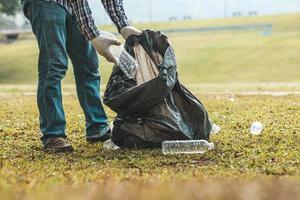 un uomo sta raccogliendo spazzatura in un parco, non gettare spazzatura nella spazzatura può rovinare la bellezza dell'area del giardino e causare anche il riscaldamento globale e danneggiare gli animali. concetto di pulizia nelle aree pubbliche. foto