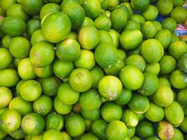 primo piano di limoni freschi e verdi in vendita sul mercato foto