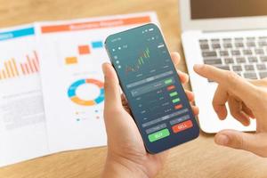 gli uomini d'affari lavorano con gli investimenti del mercato azionario utilizzando gli smartphone per analizzare i dati di trading. smartphone con grafico di borsa sullo schermo. mercato azionario finanziario. foto