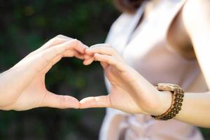 primo piano di coppia felice divertimento facendo gesto a forma di cuore con la mano all'aperto insieme, uomo e donna con relazione sentimento amore con simbolo e segno, amante e concetto romantico. foto