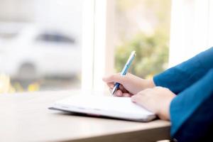 primo piano mano donna scrittrice pensando idea e scrivendo su taccuino o diario con felice, lo stile di vita di una ragazza asiatica è studente, lavoro di pianificazione femminile, istruzione e concetto di business. foto