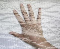 mano di una giovane donna avvolta in una pellicola di plastica che mostra diversi gesti foto