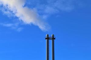 inquinamento dell'industria da ciminiere di fabbrica in un cielo blu profondo foto