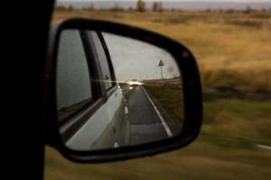 il riflesso della strada nello specchietto retrovisore laterale con gocce di pioggia. concetto di viaggio. foto