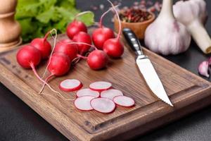delizioso ravanello rosso fresco come ingrediente per fare l'insalata di primavera sul tagliere di legno foto