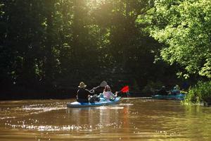 gita in kayak in famiglia. uomo e donna e coppia di anziani barca a remi senior e seniora sul fiume, un'escursione in acqua, un'avventura estiva. turismo ecologico ed estremo, stile di vita attivo e sano foto