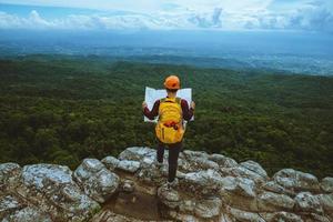 gli asiatici della donna viaggiano rilassati durante le vacanze. guarda la mappa esplora le montagne foto