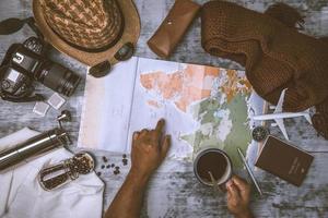 vacanza di pianificazione turistica con l'aiuto della mappa del mondo e della bussola e della tazza di caffè con macinacaffè con altri accessori da viaggio. prepararsi per il viaggio. concetto di pianificazione del viaggio vacanza con mappa foto