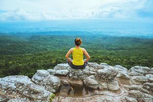 la donna asiatica si rilassa in vacanza. viaggiare rilassati. gioca se lo yoga. sulla scogliera di roccia della montagna. natura delle foreste di montagna in Thailandia
